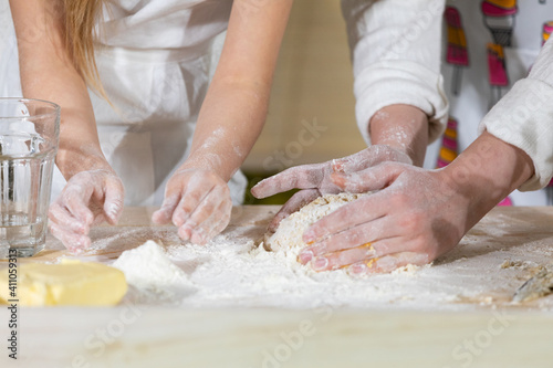 In one of the last stages, mother and daughter knead and knead a cake that will serve as a pizza cake. Mother and baby do the dough together in the kitchen.