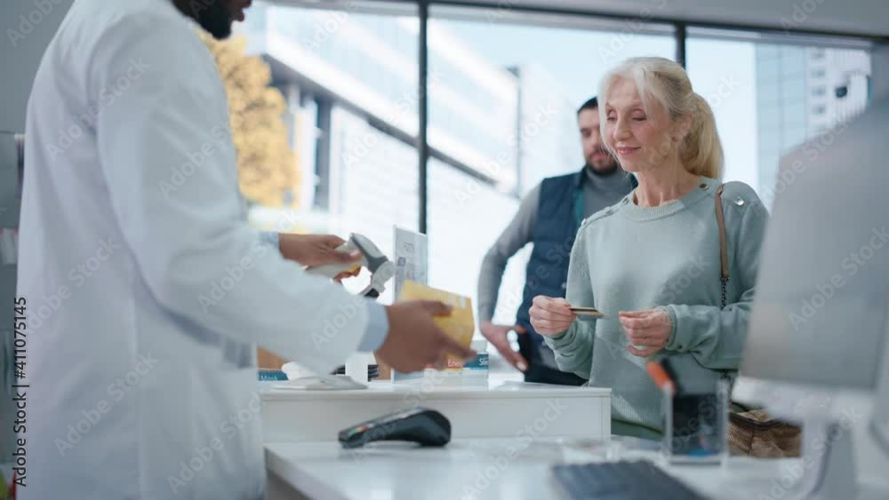 Pharmacy Drugstore Checkout Cashier Counter: Black Male Pharmacist Service Senior Female Customer Buying Prescription Medicine Package and Paying Using Contactless Credit Card Holding it to Terminal Pharmacy Drugstore Checkout Cashier Counter: Black Male Pharmacist Service Senior Female Customer Buying Prescription Medicine Package and Paying Using Contactless Credit Card Holding it to Terminal