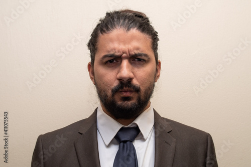 Man in a suit and blue tie with doubt or anger expression, with a single color background