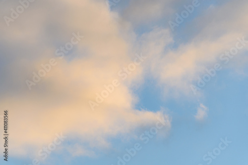 Late afternoon cloudscape, glowing clouds against a blue sky, as a nature background 