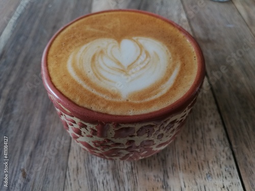 a cup of cappuccino with latte art on wood table. top angle view 