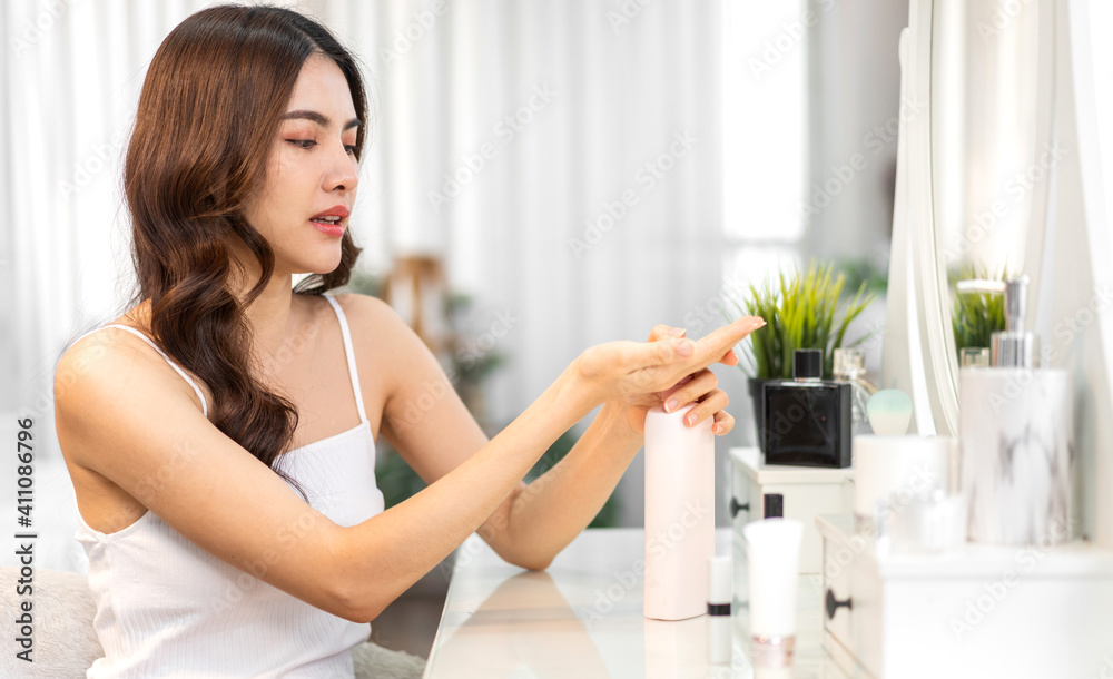 Smiling of young beautiful pretty asian woman clean fresh healthy white skin looking at mirror.asian girl holding body lotion and applying moisturizing cream at home.spa and beauty concept