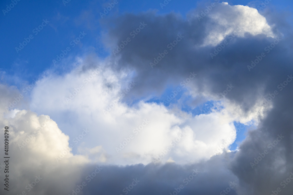 Dramatic and glowing cloudscape of blue sky and white and gray clouds as a nature background
