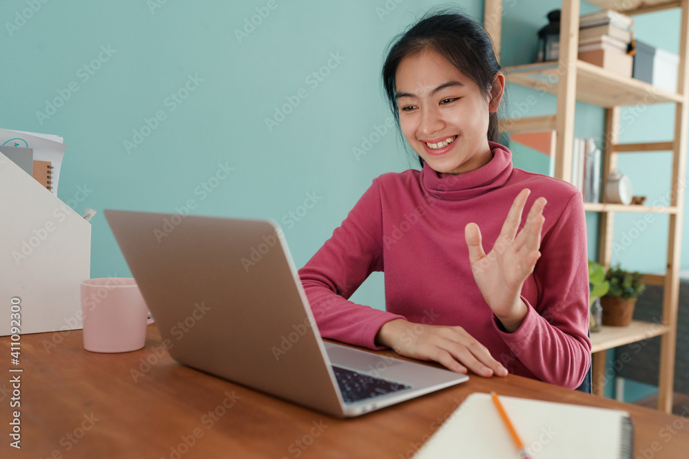Happy Asian student waving in greeting online tutor on a laptop computer at home. Happy Asian student waving in greeting online tutor on a laptop computer at home.