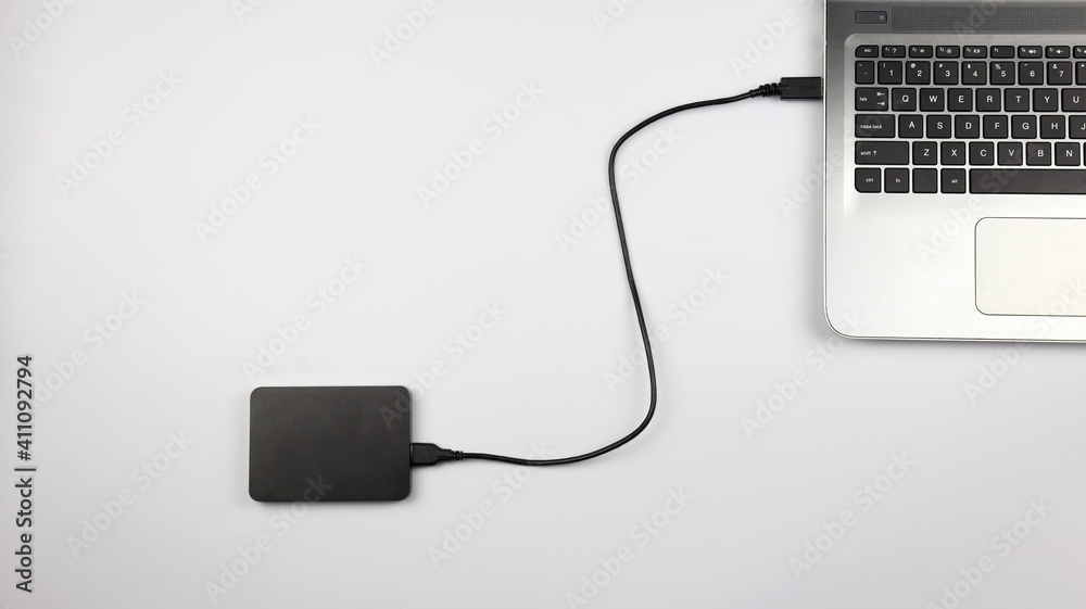 External hard drive connected to laptop on white surface. Concept for office, business, education and presentation External hard drive connected to laptop on white surface. Concept for office, business, education and presentation