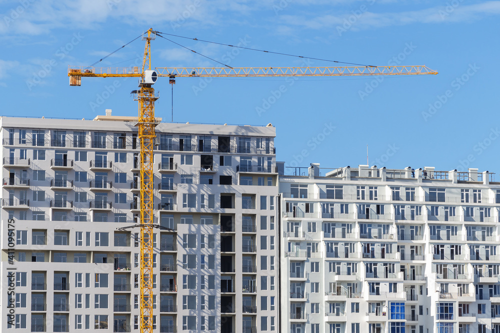 Tower construction crane in front of finished  apartment building.