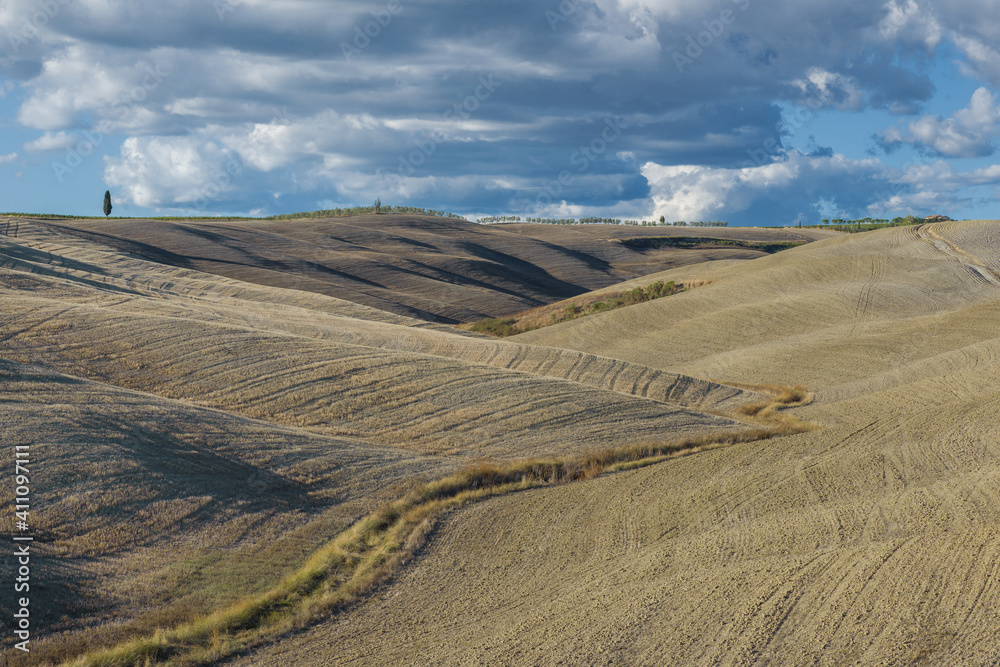 Harvested hilly fields under a September cloudy sky. Tuscany, Italy