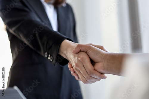 Two businesswomen shake hands after accepting a business proposal together, a handshake is a universal homage, often used in greeting or congratulations. © kamiphotos