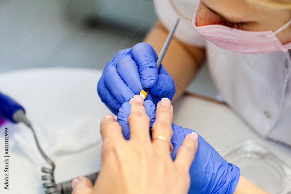 Professional manicure. Closeup shot of a woman in a nail salon. Professional nail polish with electric tips, selective focus