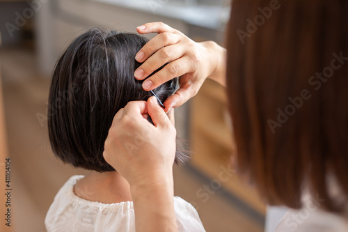 家の中で母親が娘の髪の毛をセットしている mother hair child