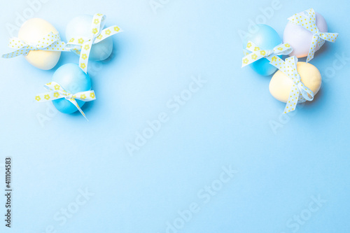 Easter flat. Colorful egg with tape ribbon on pastel blue background in Happy Easter decoration. Spring holiday top view concept.
