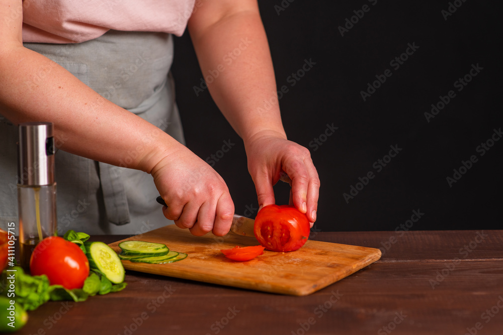 The chef cuts fresh vegetables on a wooden board. Cooking a burger. The chef cuts fresh vegetables on a wooden board. Cooking a burger.