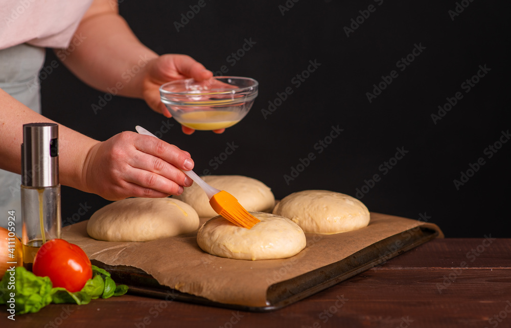 The chef prepares the burger buns for baking by brushing them over with yolk. Cooking a burger. The chef prepares the burger buns for baking by brushing them over with yolk. Cooking a burger.