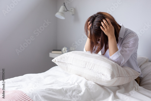 ベッドで女性が頭を抱えて悩んでいる　woman bed photo