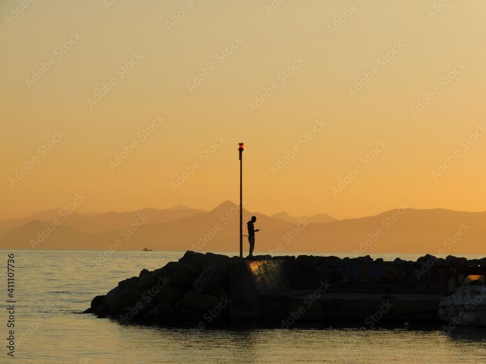 Loneliness. A solitary man looks at his mobile phone, on a sea wall