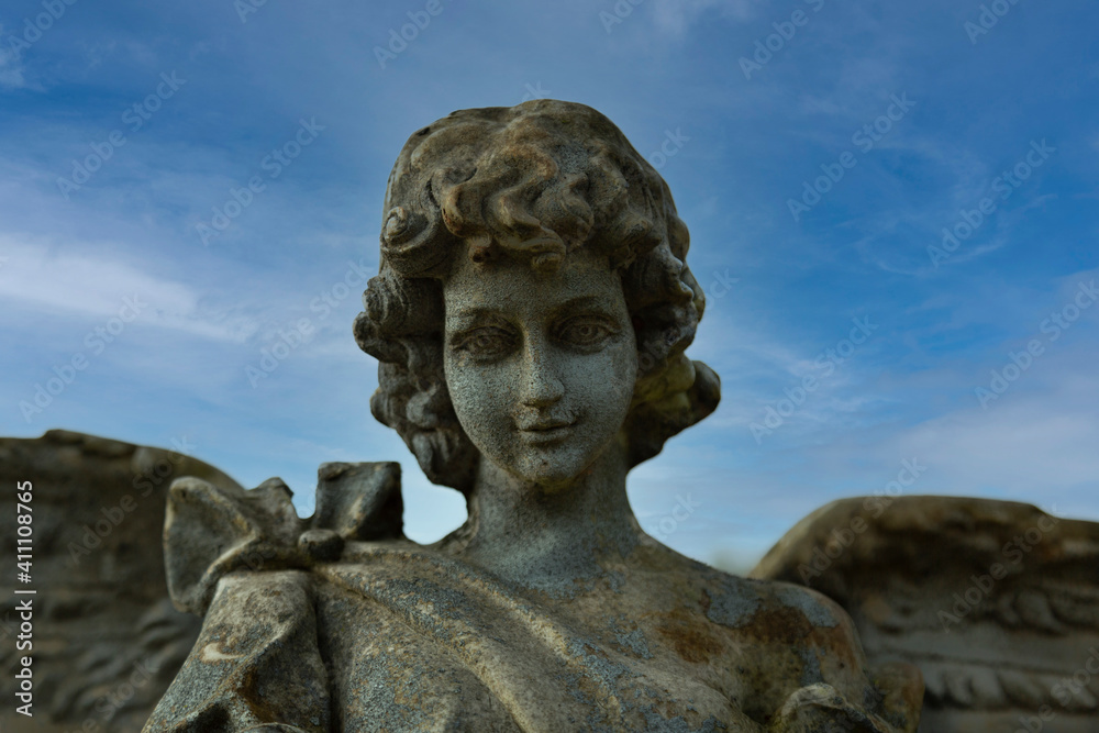 Partial Upward View of an Angel Statue Against Blue Clouded Sky Backdrop 