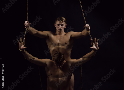 Man rope. Young twins athletic sexual guys with powerful shoulders, abdomen and chest, abs or six pack. Male hunk with naked body, bare torso.