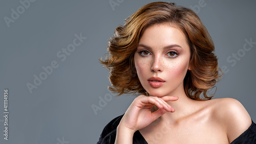 Beautiful brown haired with stylish short hairstyle. Woman with a  curly hair. Beautiful young woman with freckles on face.  Closeup portrait of an attractive girl  with a brown makeup.