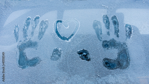 Close-up of a heart and a handprint on a car window. Winter weather