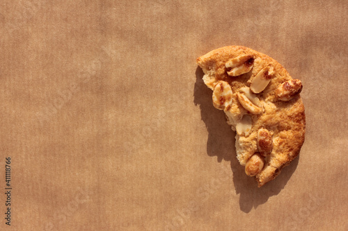 Piece of peanut cookie on kraft paper. Close-up of homemade pastry on brown background with copy space