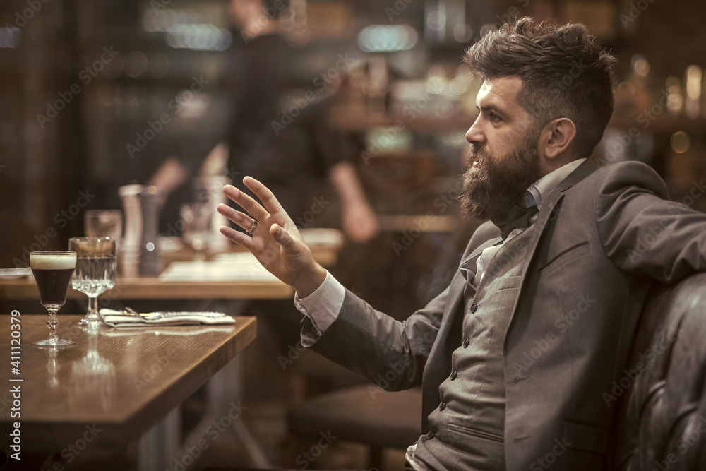 Confident bar customer speak in cafe. Date or business meeting of hipster in pub. Bearded man in restaurant. Confident bar customer speak in cafe. Date or business meeting of hipster in pub. Bearded man in restaurant.