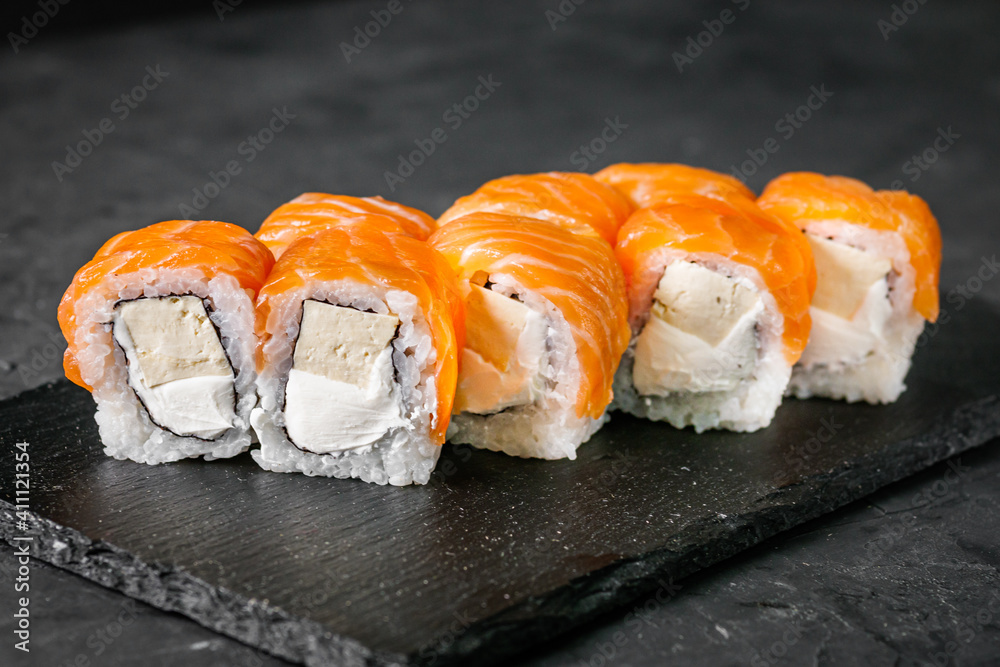 appetizing sushi roll philadelphia with tofu and salmon on a black stone plate appetizing sushi roll philadelphia with tofu and salmon on a black stone plate