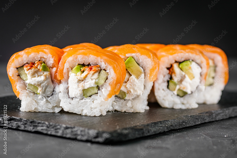 appetizing sushi roll philadelphia with avocado cheese eel cucumber and salmon on a black stone plate