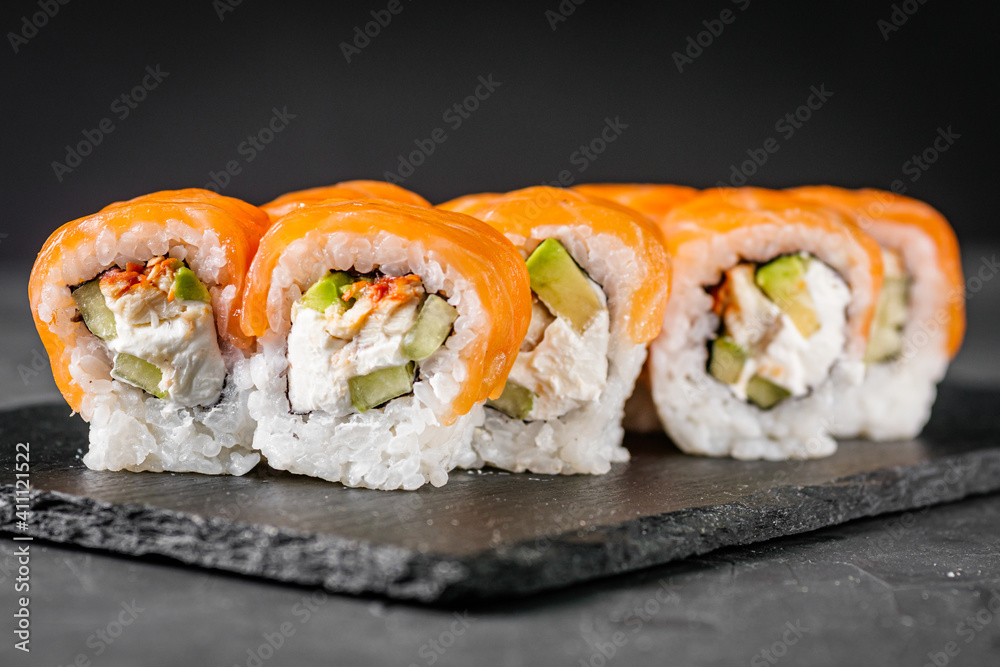 appetizing sushi roll philadelphia with avocado cheese eel cucumber and salmon on a black stone plate appetizing sushi roll philadelphia with avocado cheese eel cucumber and salmon on a black stone plate
