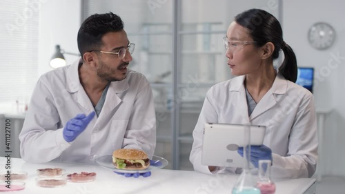 Wallpaper Mural Waist-up footage of multi-ethnic scientists inspecting and discussing burger with lab-grown meat inside sitting at table in white modern laboratory Torontodigital.ca