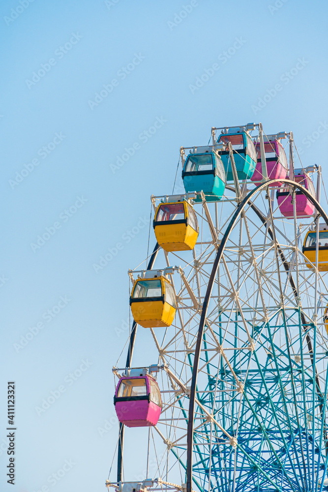 Colorful ferris wheel in an amusement park against blue sky Colorful ferris wheel in an amusement park against blue sky