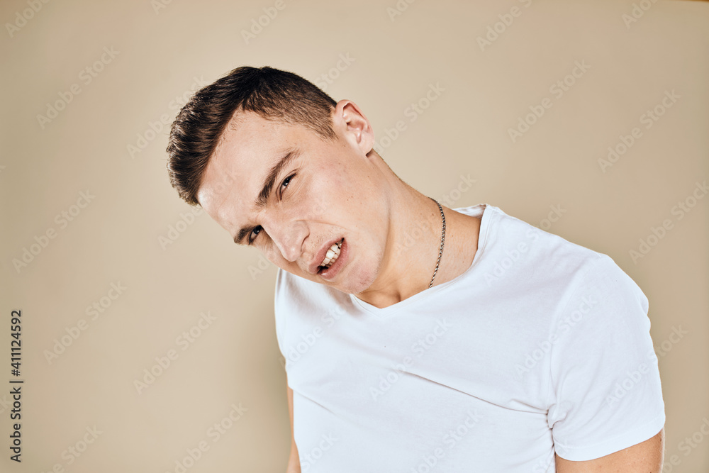 Man with displeased facial expression emotions white t-shirt gestures with hands beige background Man with displeased facial expression emotions white t-shirt gestures with hands beige background