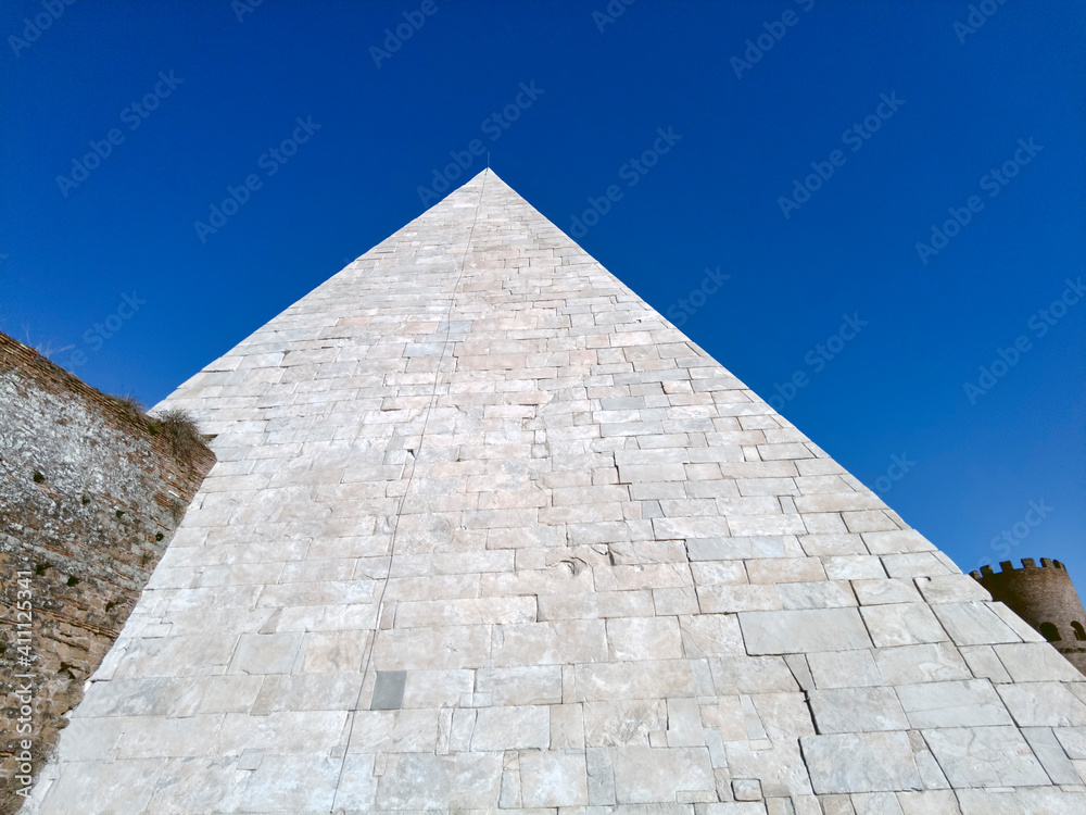 White marble of ancient Pyramide Cestia in blue sky background the famous sepulcher building at 12 A.C. houses the tomb of Gaio Cestio Epulone its located in Rome White marble of ancient Pyramide Cestia in blue sky background the famous sepulcher building at 12 A.C. houses the tomb of Gaio Cestio Epulone its located in Rome
