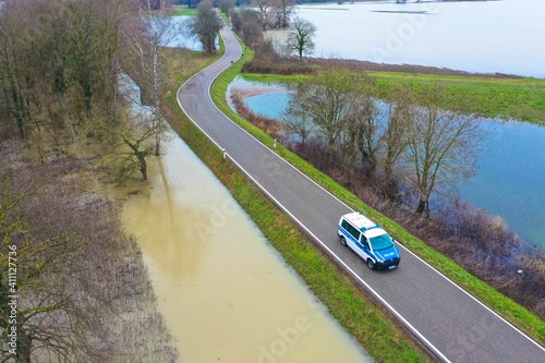 A police car patrols an asphalt country road during floods. Flood disaster in winter. photo