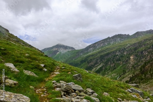 stony trail over a hill while hiking in the mountains in the summer