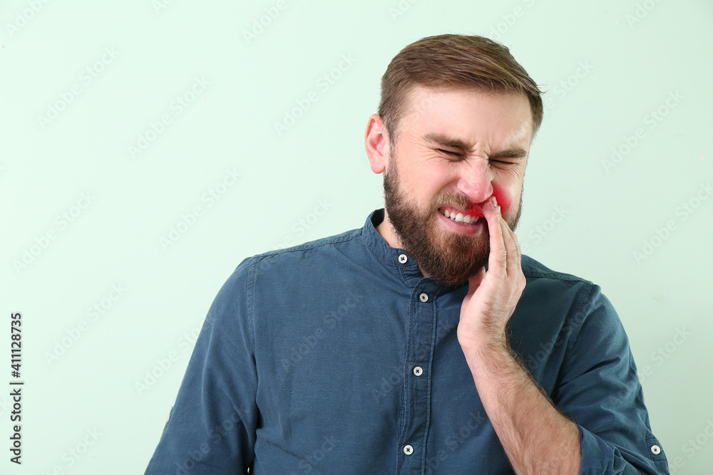 Young man suffering from toothache on color background Young man suffering from toothache on color background