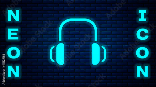 Glowing neon Winter headphones icon isolated on brick wall background. Earmuffs sign. Vector.