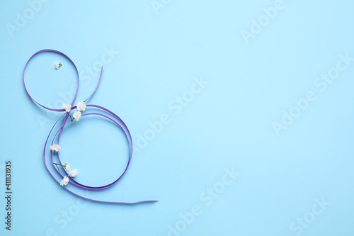 Figure 8 made of violet ribbon on color background. International Women's Day celebration