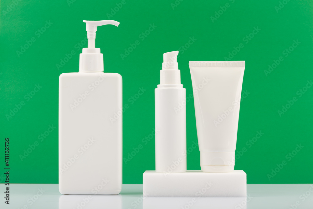 Skincare products in white plastic tubes on white table against green background. Concept of organic beauty products for fresh, young looking skin. Moisturizing or anti aging products. Skincare products in white plastic tubes on white table against green background. Concept of organic beauty products for fresh, young looking skin. Moisturizing or anti aging products.