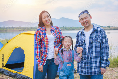 Group of asian family travel and camping at lakeside in forest ,standing all together and smile. Family and outdoor activity concept.