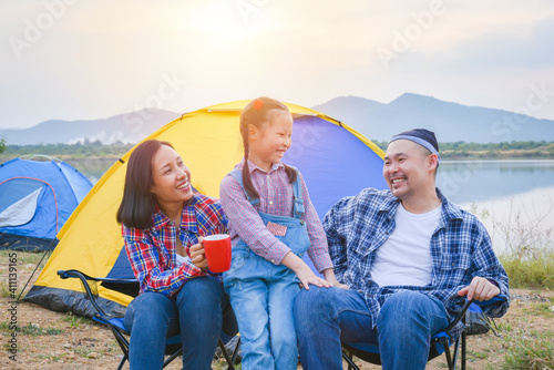 Group of asian family travel and camping at lakeside in forest ,sitting all together and smile. Family and outdoor activity concept.