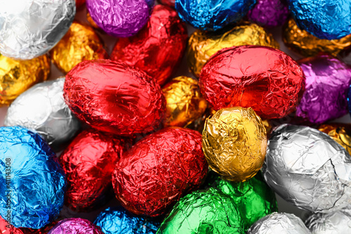 Many chocolate eggs wrapped in bright foil as background, closeup view © New Africa