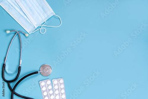 Stethoscope  protective mask and medicine packaging on a blue background. Medical banner template with copy space  header layout. Health care and medical concept.