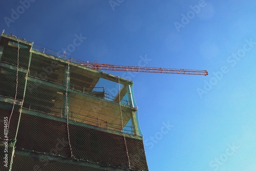 Un edificio en construcción en el barrio de Montecarmelo, Madrid, España. Grúa de construcción, andamios y redes de protección en un día de trabajo. photo