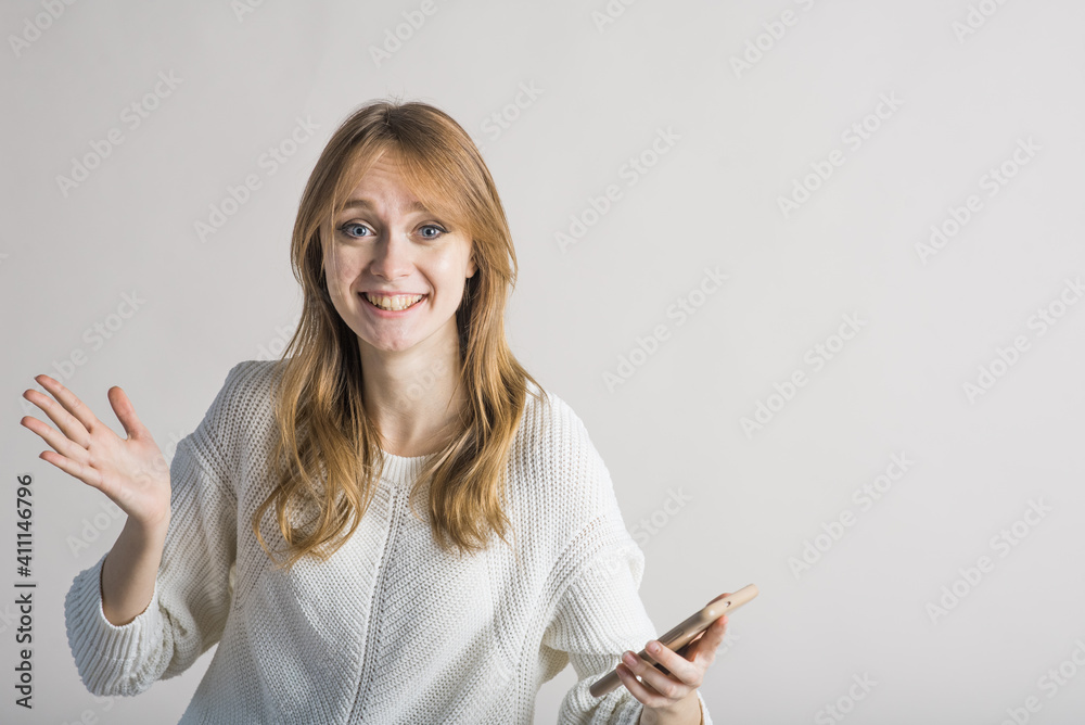Beautiful young girl on a white background in the studio rejoices at the message in the smartphone Beautiful young girl on a white background in the studio rejoices at the message in the smartphone