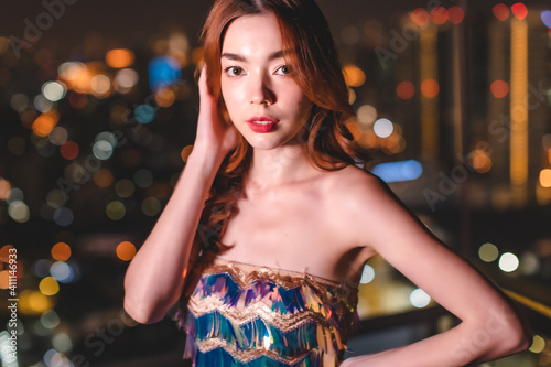 Young asian woman dancing and celebrating party new year.Young trendy ambitious woman looking intense in the camera at night next to neon light. Nightlife youth and urban atmosphere.