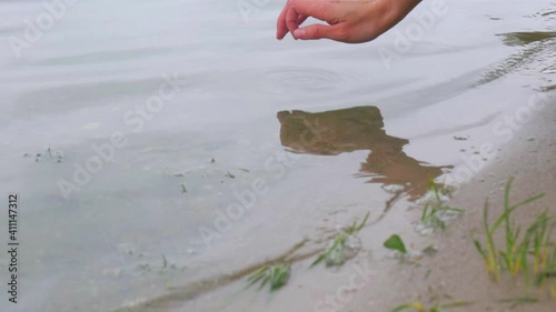 The girl touches the water on the river with her fingers. Close-up shot of a woman's hand on a background of water by the lake. photo