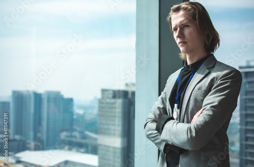 Portrait of a handsome CEO smiling.businessman in suit standing in office with hands on waist, CEO looking through window. Horizontal photo banner for website header design with copy space for text