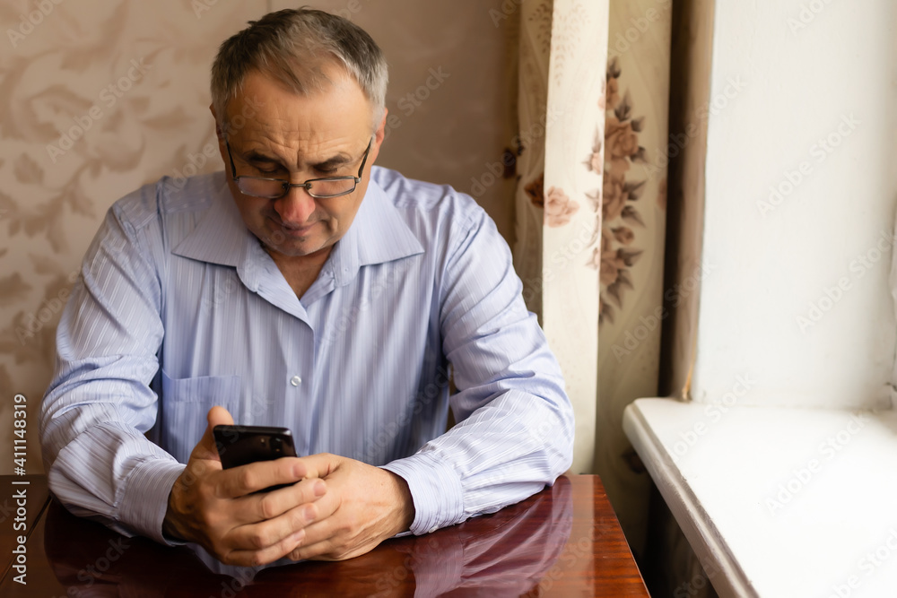 technology, people, lifestyle and communication concept - happy senior man dialing phone number and texting on smartphone at home technology, people, lifestyle and communication concept - happy senior man dialing phone number and texting on smartphone at home