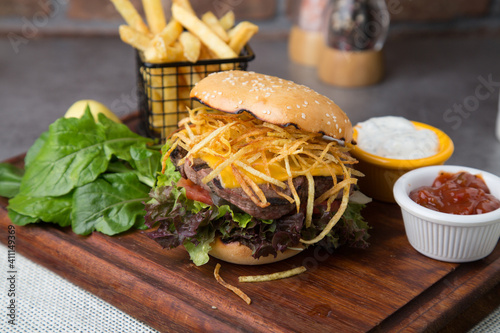 Burger with shoestring fried potatoes and rocket leaves 