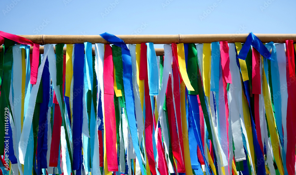 Colorful textile ribbons are hanging under bamboo sticks, blue sky background.  A way to recycle the material and good for decoration.  Objects and creative arts categories.  